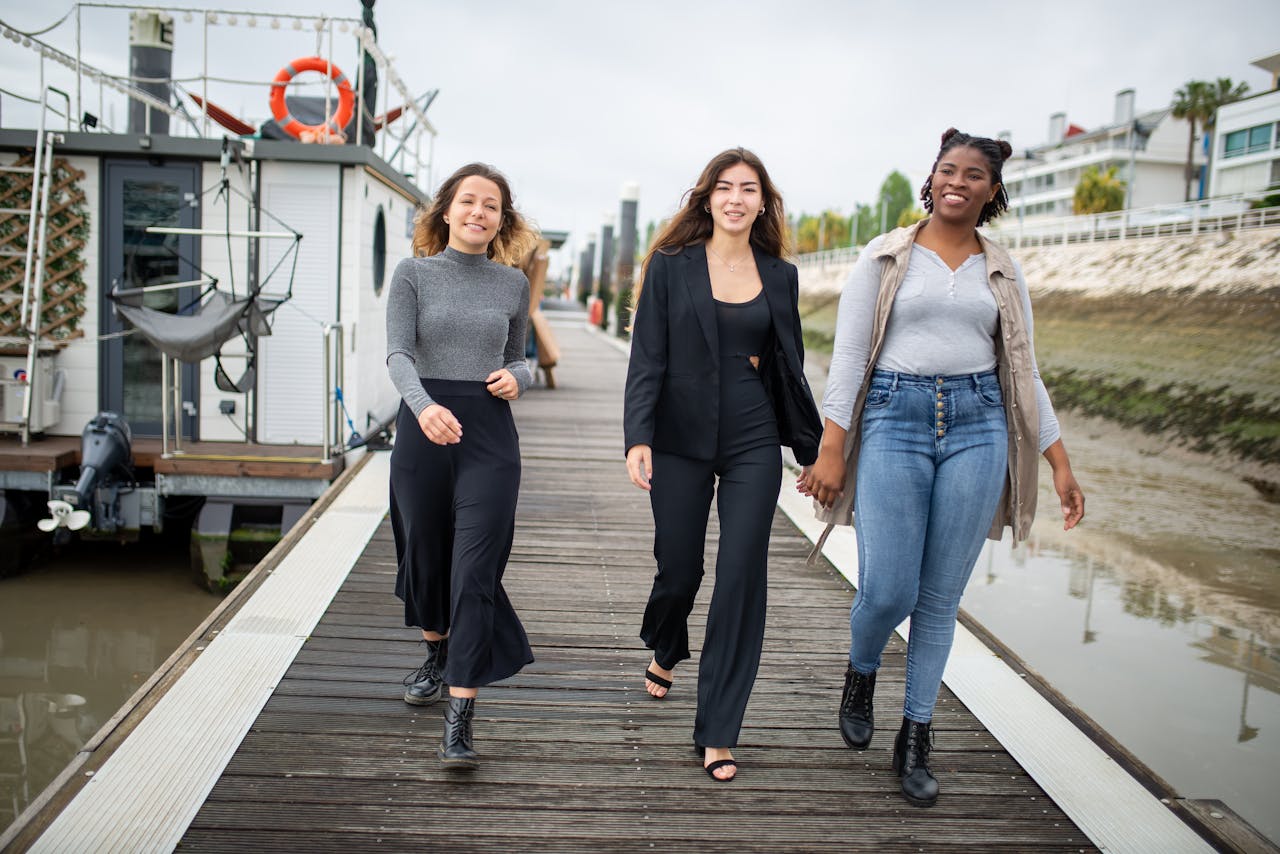 Three young women happily walking on a pier in Portugal, enjoying a moment of friendship and joy.